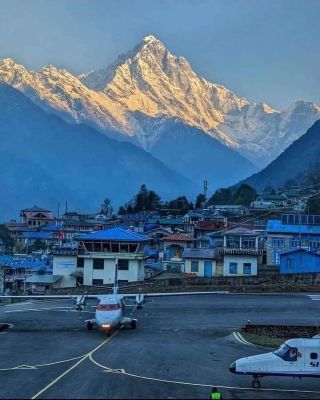 Plane at Lukla Airport with Himalayan mountains in the background.